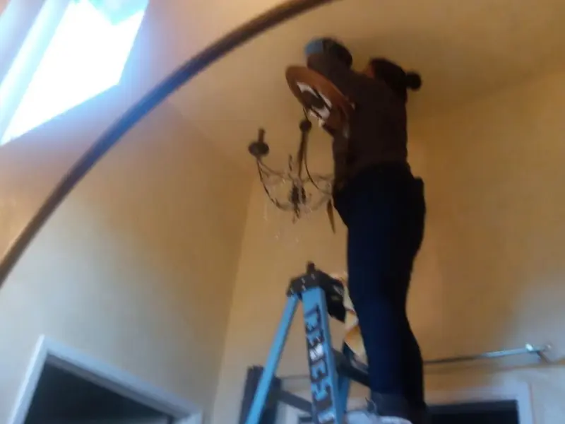 Electrician installing a chandelier in a North East residence